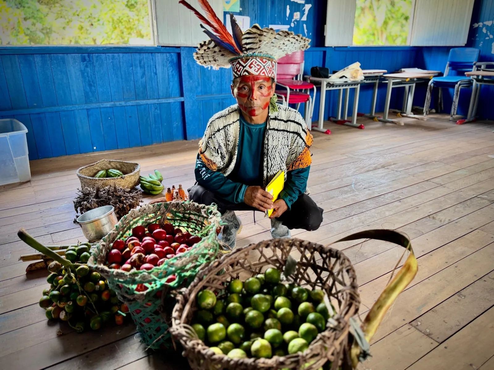 Liderança indígena ao lado de cestos com frutas e alimentos tradicionais
